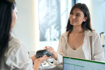 Mulher realizando pagamento via cartão. Empreendedora está viabilizando a melhor compensação de pagamento para o seu negócio.