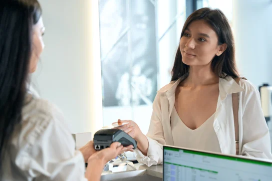 Mulher realizando pagamento via cartão. Empreendedora está viabilizando a melhor compensação de pagamento para o seu negócio.