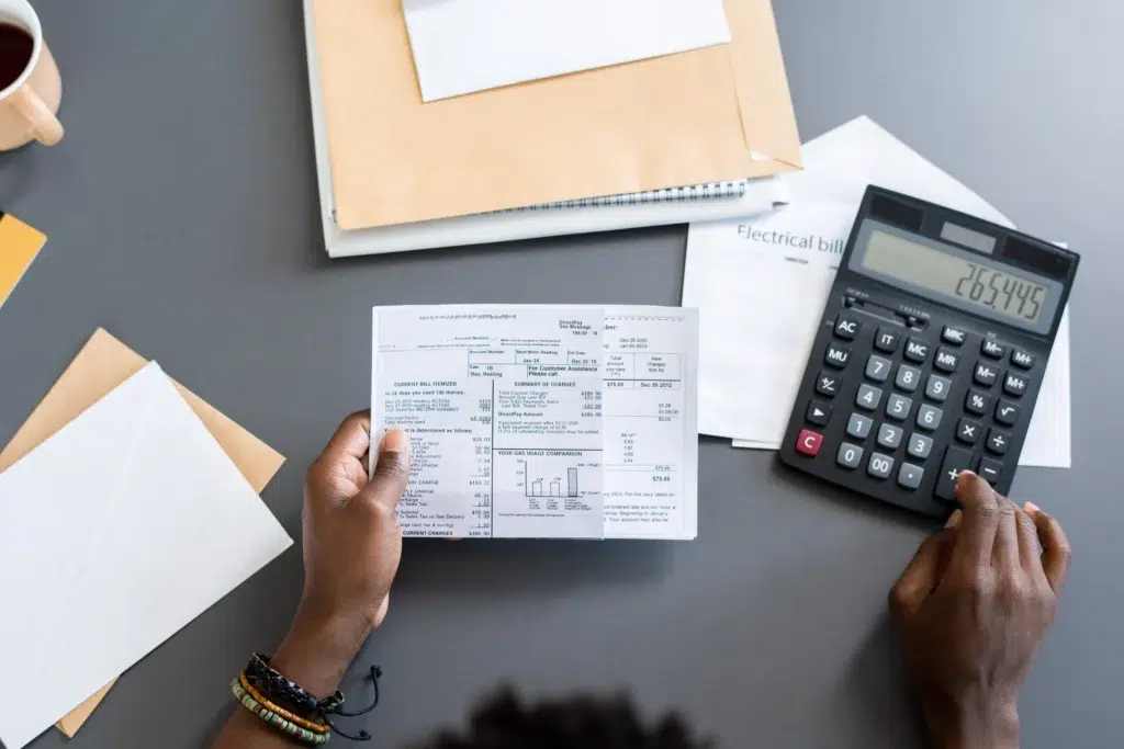 Pessoa fazendo cálculo em calculadora, a respeito do faturamento para emissão de nota fiscal.