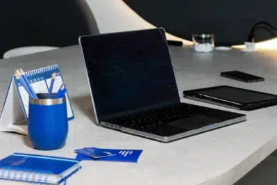 Notebook em mesa com acessórios na cor azul, representando o aumento do IOF para empresas.