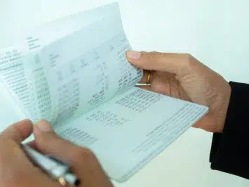 Pessoa segurando e analisando diversos tipos de nota fiscal em mãos.