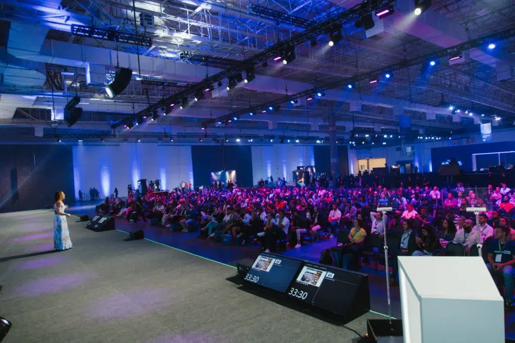 Foto de uma palestra para exemplificar os bastidores do Asaas Connect 2023, em que mostra uma palestrante e a plateia.