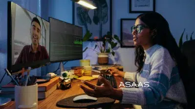 Atendente em frente ao notebook, representando o suporte do contato Asaas em um ambiente de atendimento.