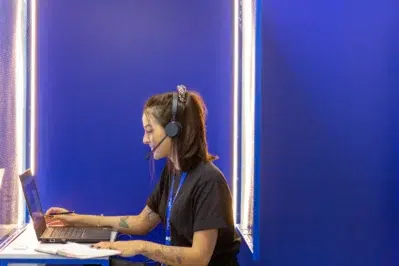 Atendente com headset em frente ao notebook, representando o suporte do contato Asaas em um ambiente de atendimento.
