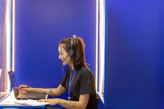 Atendente com headset em frente ao notebook, representando o suporte do contato Asaas em um ambiente de atendimento.