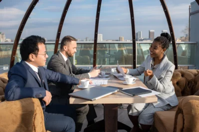 Três profissionais conversando no topo de um prédio corporativo sobre uma rodada de investimento.