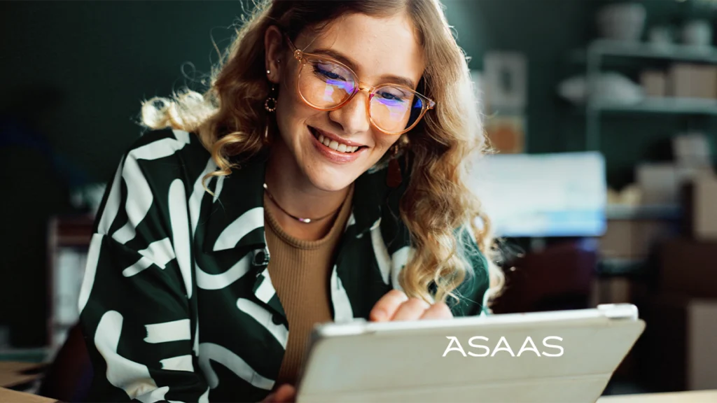 Mulher olhando para baixo usando computador pesquisando as taxas asaas.