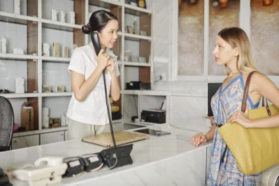 Recepcionista ao telefone atendendo cliente no balcão, ilustrando o que é essencial para um bom atendimento ao cliente.