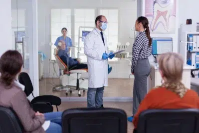 Dentista explicando opções de parcelar tratamento no boleto para paciente em consultório odontológico.