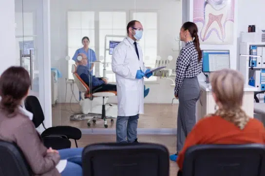 Dentista explicando opções de parcelar tratamento no boleto para paciente em consultório odontológico.