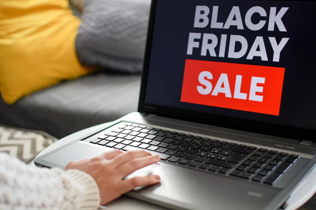 Mão mexendo em notebook com tela escrito “Black Friday”. A pessoa está desconfiada se são golpes da Black Friday ou ofertas legítimas.
