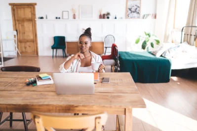 Pessoa em home office trabalhando no notebook com uma xícara na mão, pois possui trabalho remoto e híbrido.