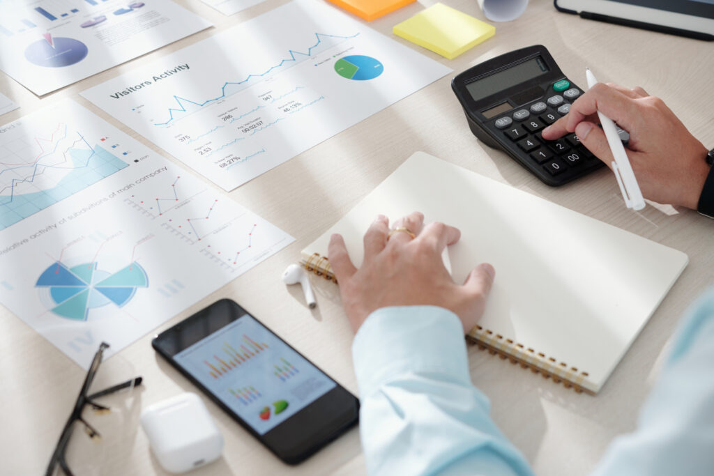 Empreendedor mexendo em calculadora e anotando em papel, enquanto aprende como calcular a necessidade de capital de giro.