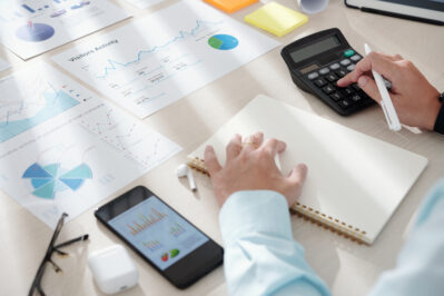 Empreendedor mexendo em calculadora e anotando em papel, enquanto aprende como calcular a necessidade de capital de giro.