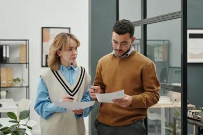 Dois empreendedores conversando e olhando para uma fatura, já que Asaas lança cobrança em grupos.