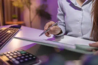 Profissional analisando anotações e calculadora no escritório, planejando estratégias de como melhorar o faturamento da empresa.