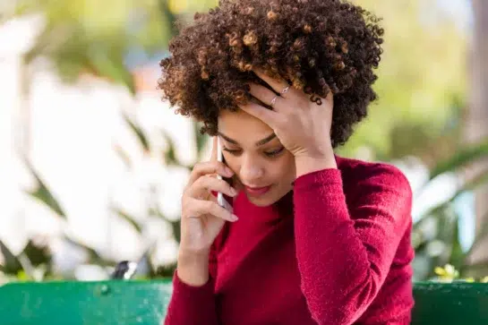 Mulher preocupada enquanto fala no telefone, por estar sendo vítima de golpes de engenharia social.