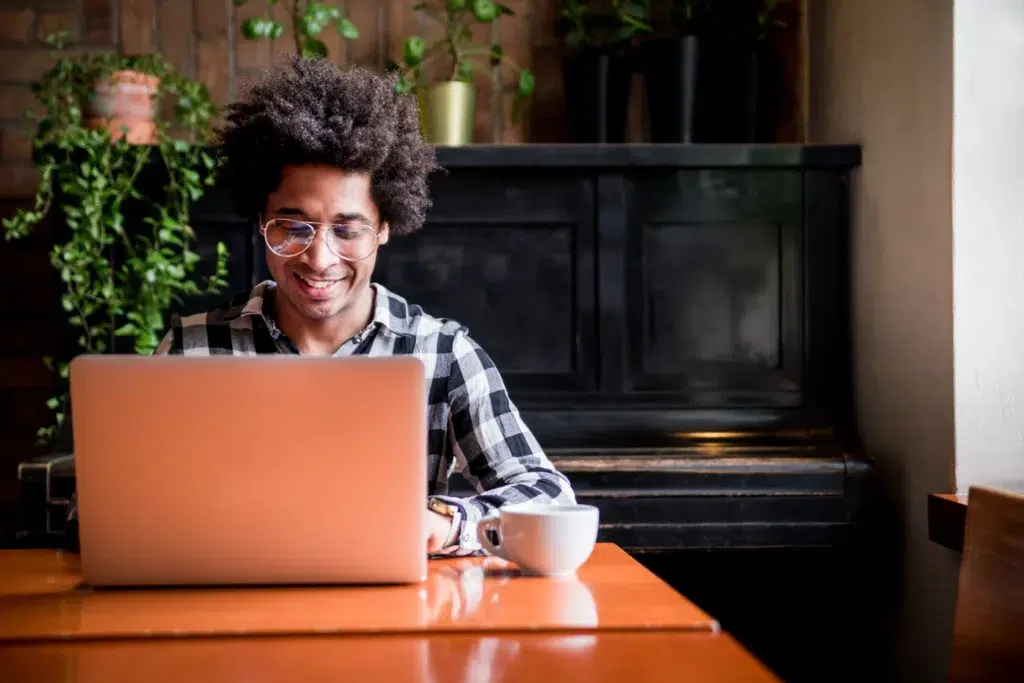 Homem sentado na mesa com laptop enquanto sorri e procura como declarar renda informal no Imposto de Renda.