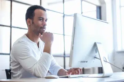 Empreendedor mexendo no computador, pesquisando se existem plataformas de pagamentos com webhooks no Brasil
