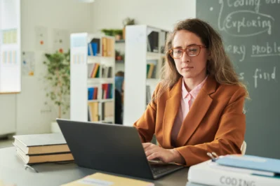 Diretora mexendo em computador, entendendo sobre inadimplência na escola particular
