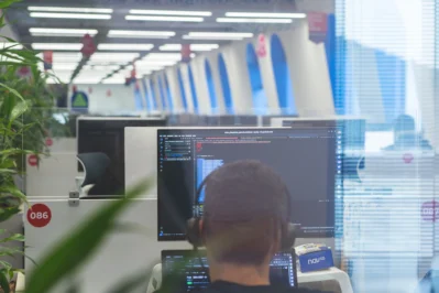 Funcionário utilizando o computador enquanto faz código, com adoção de IA em RH.