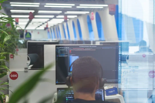 Funcionário utilizando o computador enquanto faz código, com adoção de IA em RH.