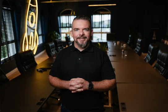 Startups entrevista Diego Contezini, representado na foto enquanto sorri e usa uma camisa polo preta.