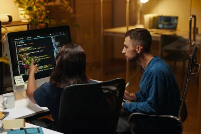 Dois desenvolvedores em frente a um computador com códigos de programação enquanto checam que o Asaas oferece ecossistema para apoiar desenvolvedores.